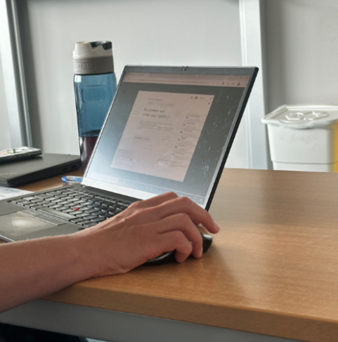 Zu sehen ist eine Andeutung einer Person, die am Laptop arbeitet